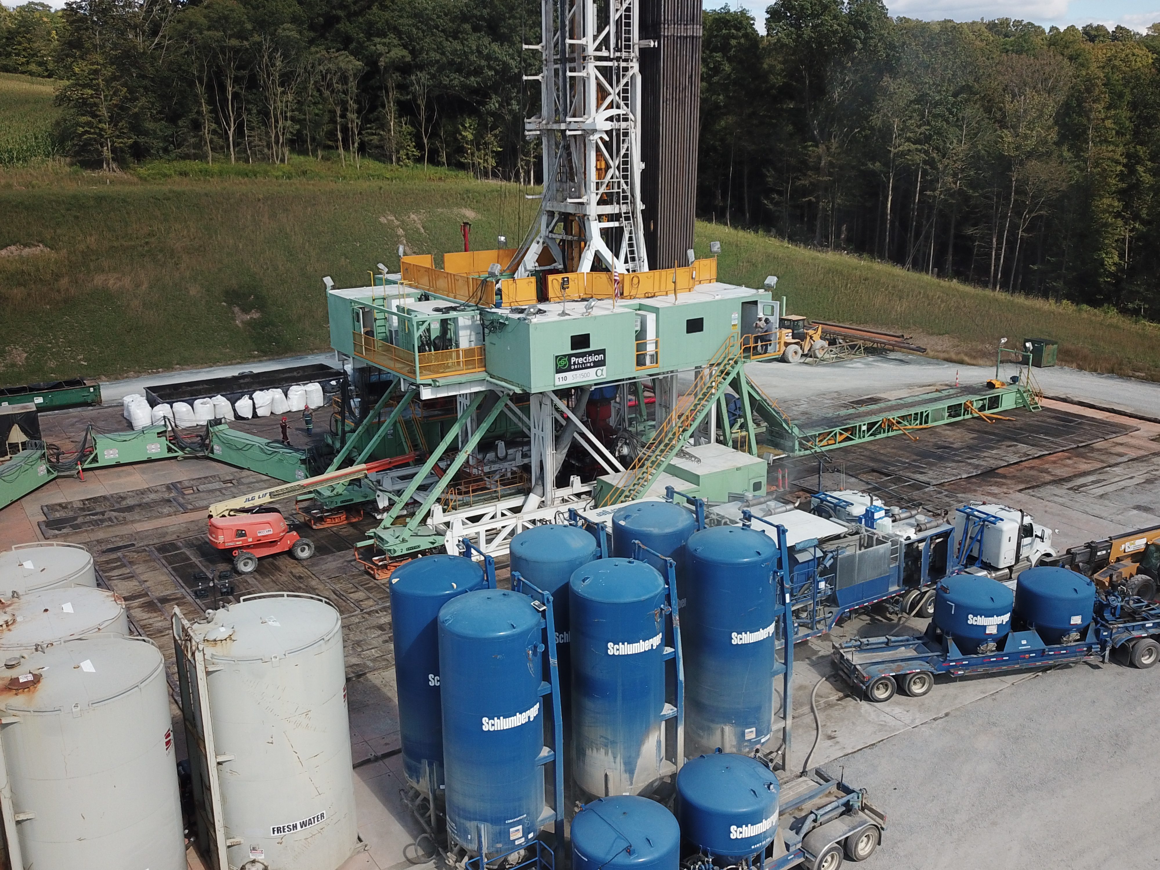 Work site with numerous trucks, containers, and a mobile crane