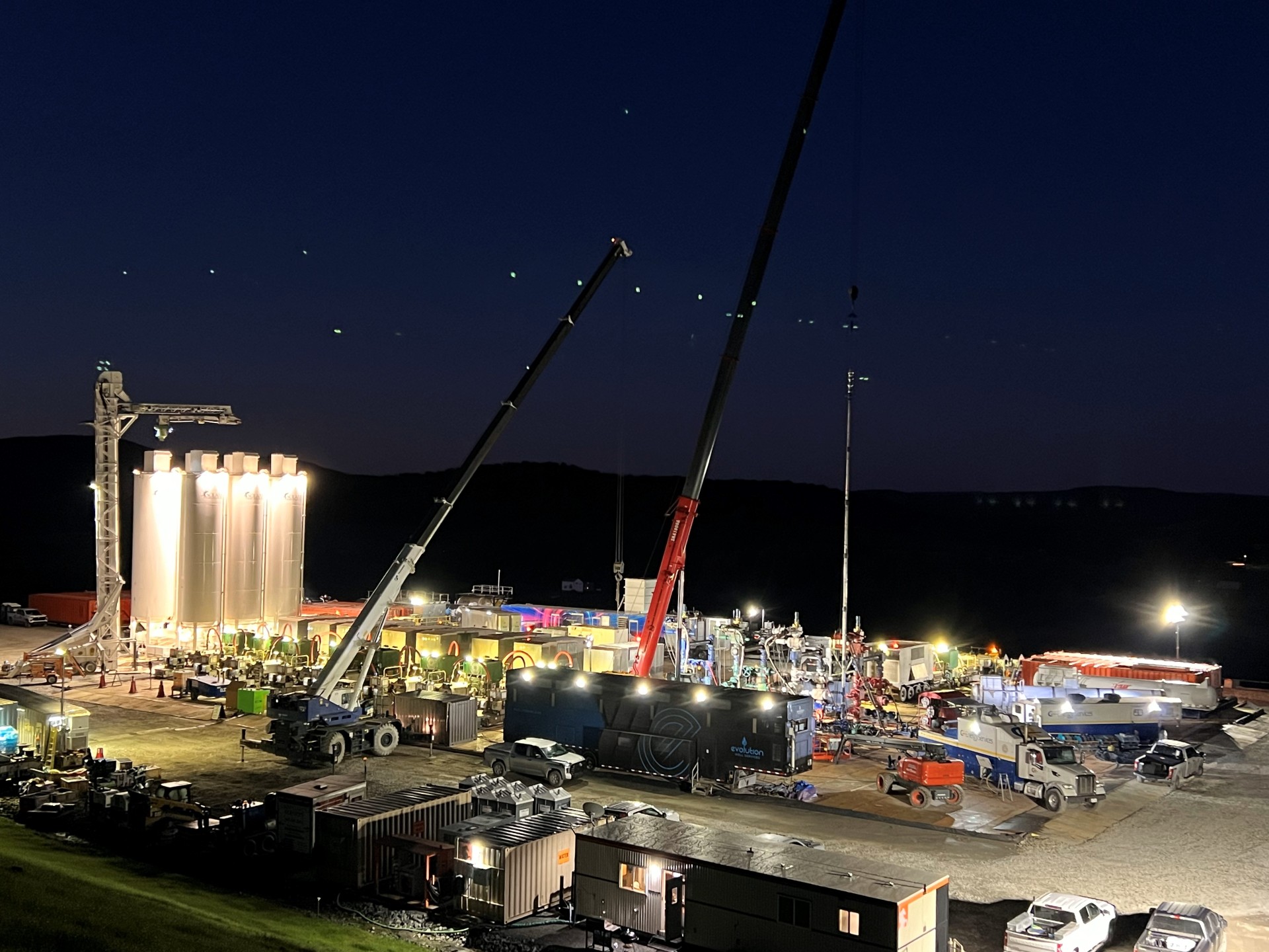 Work site with numerous trucks, containers, and a mobile crane