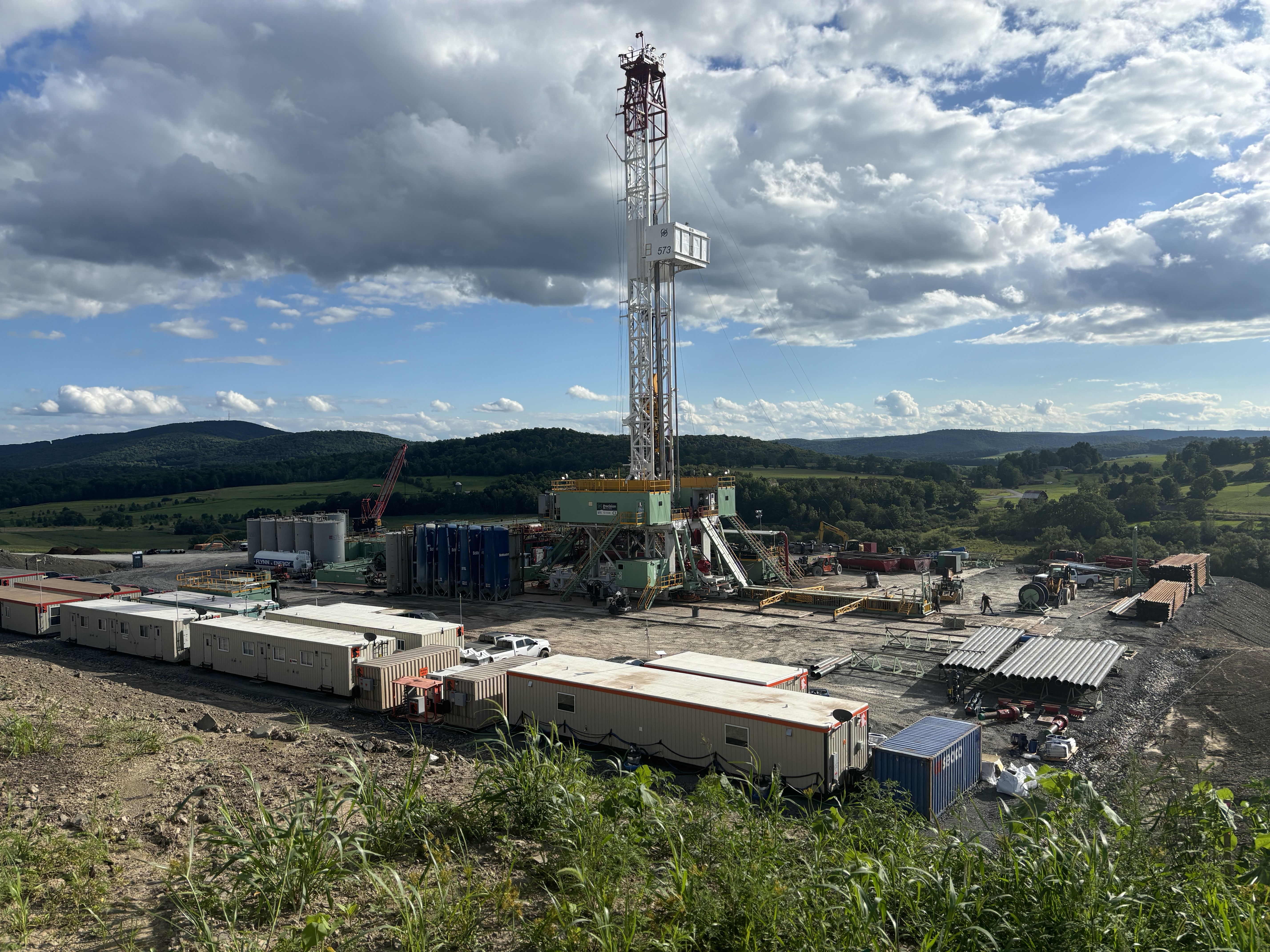 Work site with numerous trucks, containers, and a mobile crane