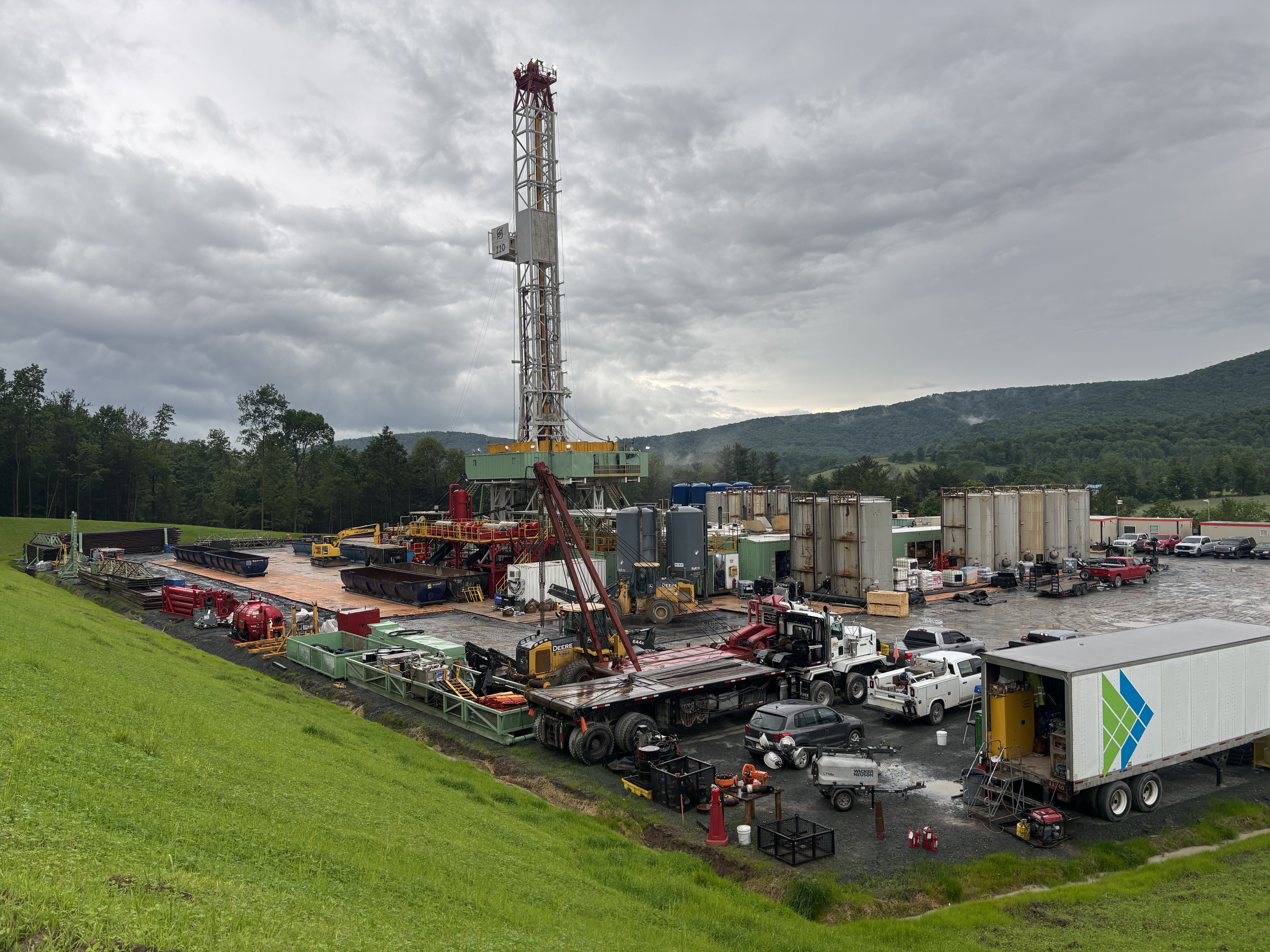 Work site with numerous trucks, containers, and a mobile crane