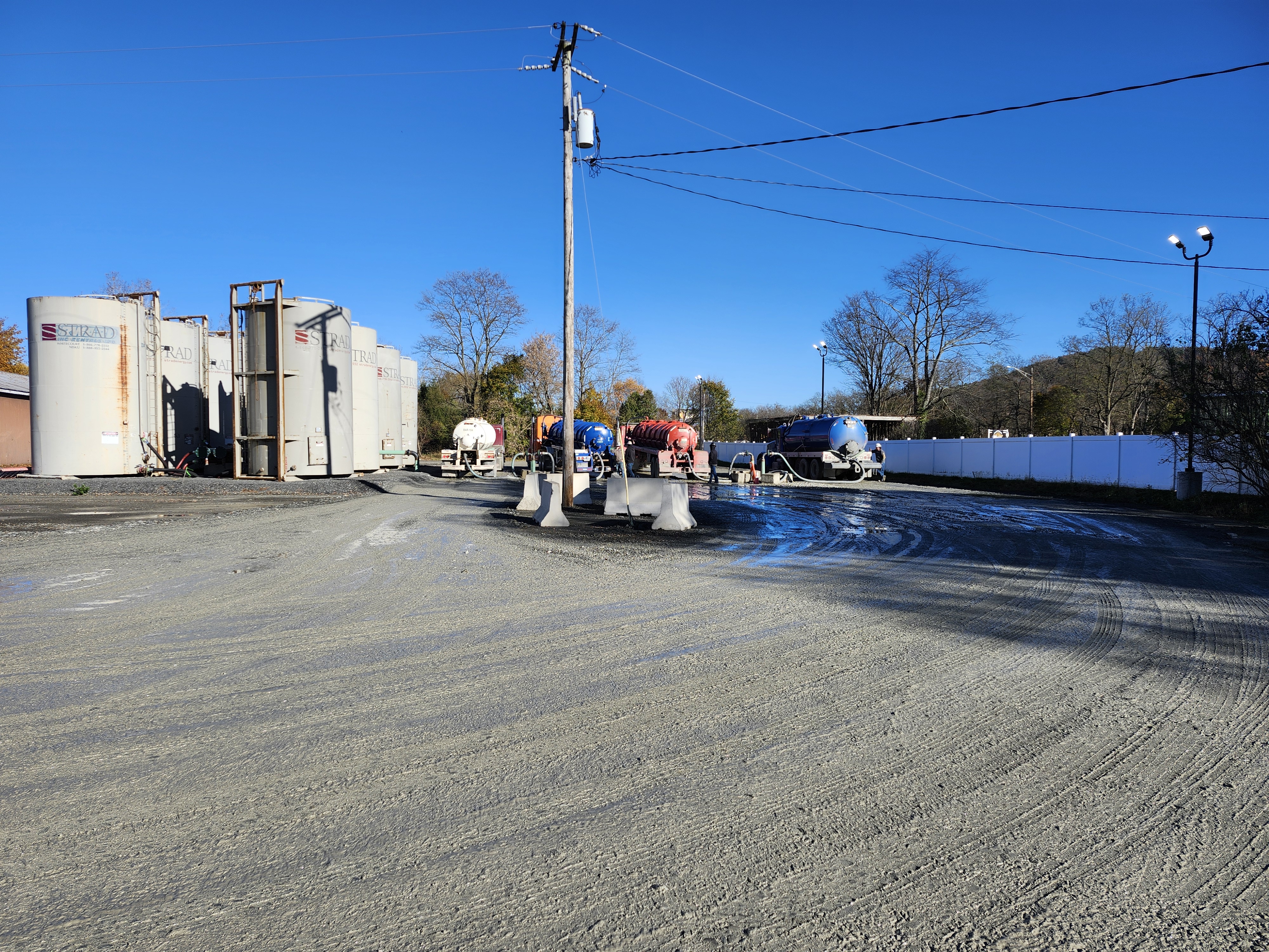 Work site with numerous trucks, containers, and a mobile crane